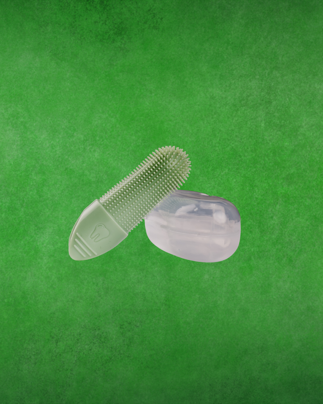 A light green silicone finger brush with a textured, brush-like surface and a translucent clear silicone case, shown against a textured green background.