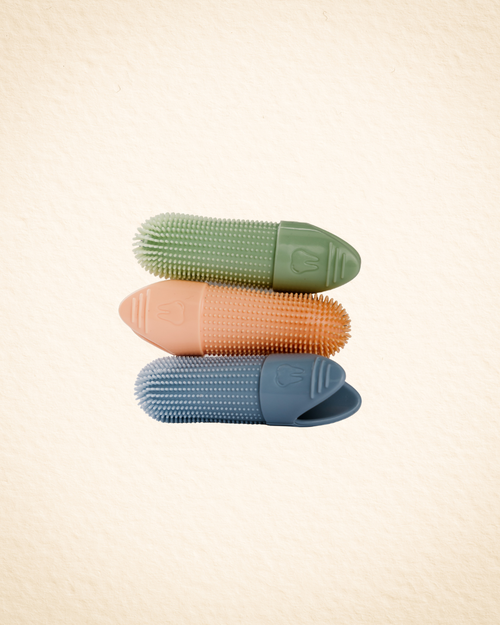 Three textured silicone slip-on finger brushes in crisp green, orange, and sky blue, stacked vertically on a light beige textured background.